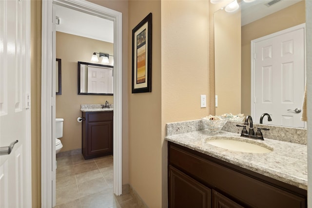 bathroom featuring tile patterned flooring, two vanities, toilet, and a sink