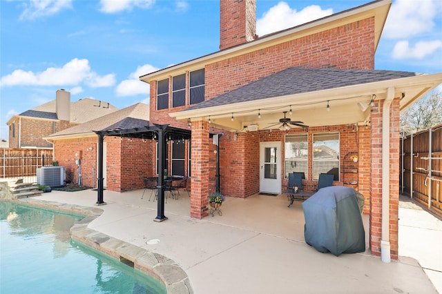 rear view of house featuring brick siding, central air condition unit, a ceiling fan, and a fenced backyard