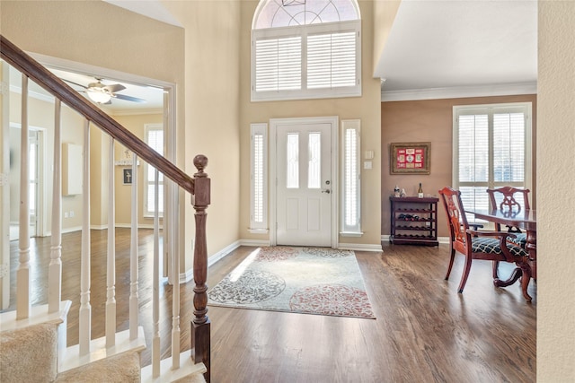 foyer featuring stairs, wood finished floors, baseboards, and ornamental molding