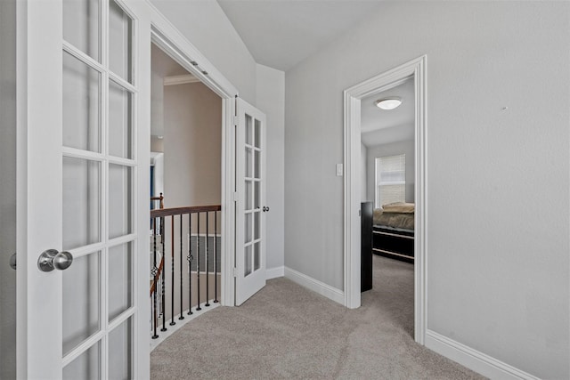 corridor featuring carpet, baseboards, and french doors