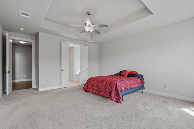 carpeted bedroom with visible vents, ensuite bath, baseboards, a raised ceiling, and ceiling fan