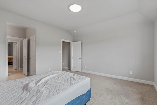 bedroom with baseboards, light colored carpet, and vaulted ceiling