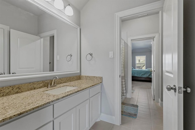 ensuite bathroom featuring tile patterned flooring, vanity, baseboards, and ensuite bathroom