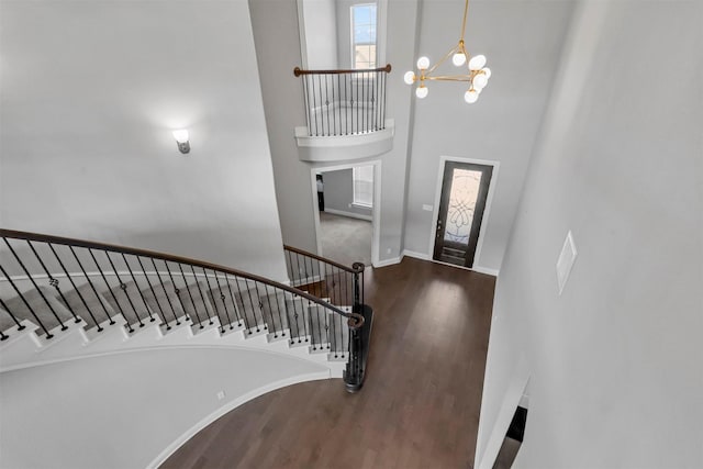 foyer featuring baseboards, wood finished floors, stairs, a towering ceiling, and an inviting chandelier