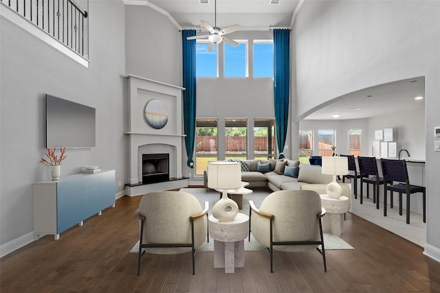 living room with baseboards, arched walkways, a fireplace with raised hearth, and wood finished floors