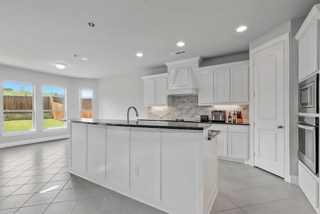 kitchen with visible vents, backsplash, appliances with stainless steel finishes, light tile patterned floors, and custom exhaust hood