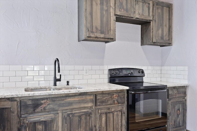 kitchen featuring light stone countertops, a sink, decorative backsplash, dark brown cabinets, and black electric range oven