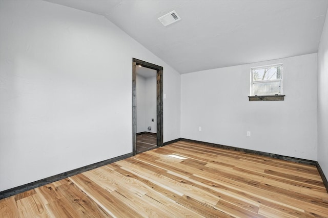 unfurnished room with visible vents, lofted ceiling, baseboards, and wood finished floors