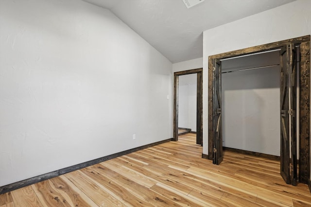 unfurnished bedroom with visible vents, baseboards, light wood-style flooring, and vaulted ceiling