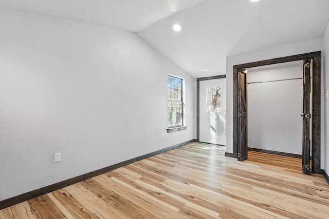 unfurnished bedroom with light wood finished floors, baseboards, and lofted ceiling