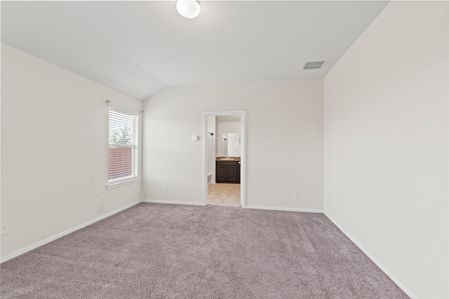 interior space with visible vents, baseboards, light colored carpet, and lofted ceiling