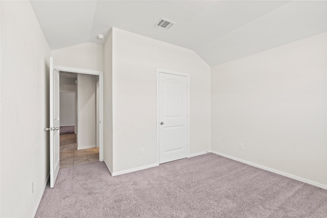 unfurnished bedroom with visible vents, carpet flooring, baseboards, and lofted ceiling