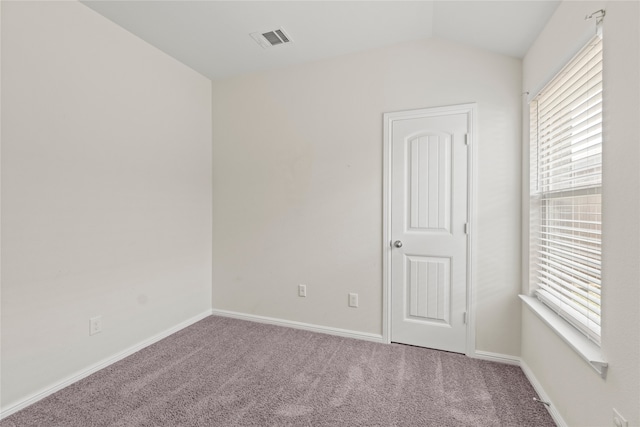 carpeted empty room featuring visible vents, baseboards, and lofted ceiling