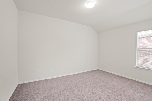 carpeted empty room with baseboards and vaulted ceiling