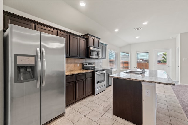 kitchen featuring visible vents, a sink, light tile patterned floors, stainless steel appliances, and a kitchen island with sink