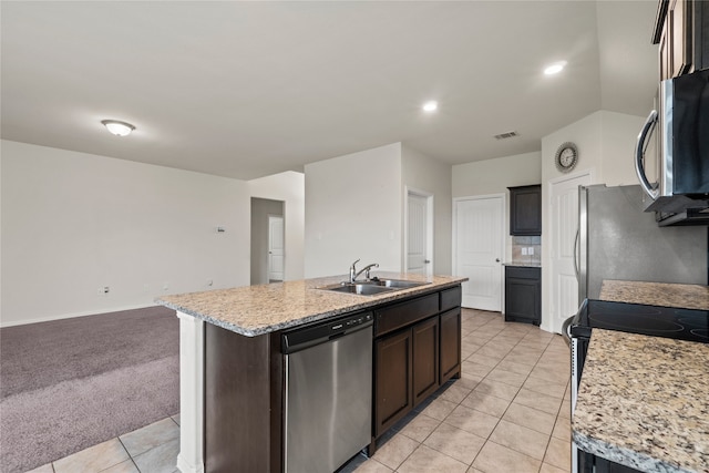 kitchen featuring light colored carpet, an island with sink, light tile patterned floors, appliances with stainless steel finishes, and a sink