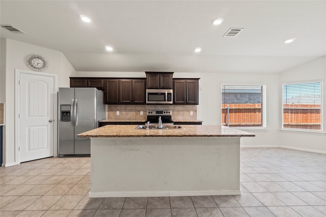 kitchen with visible vents, an island with sink, a sink, appliances with stainless steel finishes, and lofted ceiling