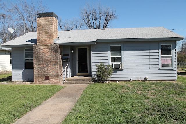 view of front of house with cooling unit, a chimney, a front lawn, and roof with shingles