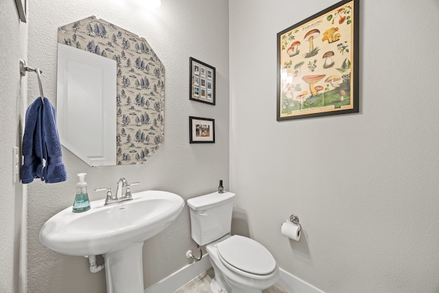 bathroom with toilet, baseboards, and a sink