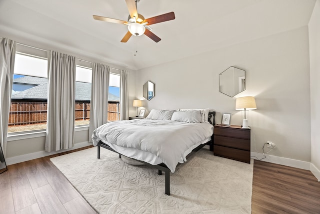 bedroom with vaulted ceiling, a ceiling fan, baseboards, and wood finished floors