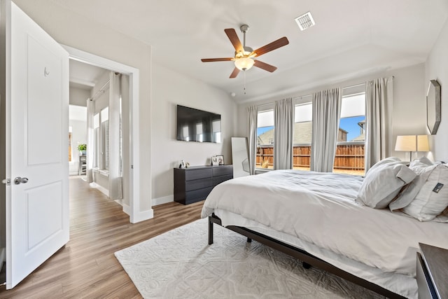 bedroom featuring wood finished floors, visible vents, baseboards, lofted ceiling, and ceiling fan