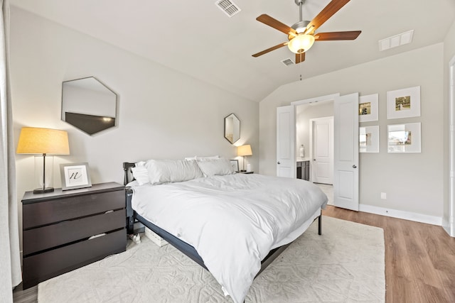 bedroom featuring vaulted ceiling, visible vents, baseboards, and wood finished floors