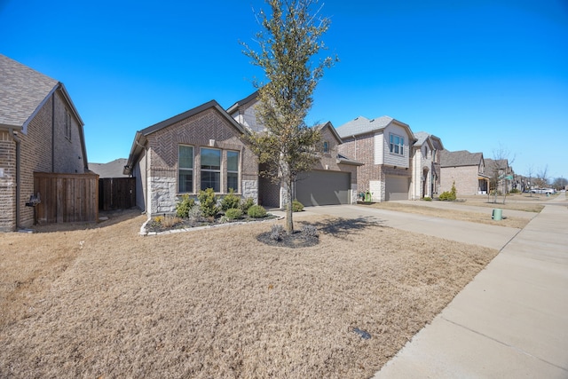 view of front of home with brick siding, fence, a residential view, stone siding, and driveway