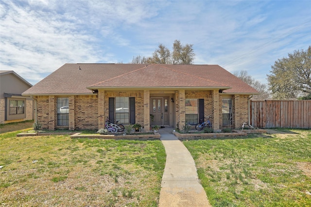 view of front facade featuring brick siding, a front yard, and fence