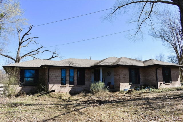 view of front facade with brick siding and a shingled roof