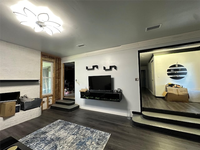 living room featuring visible vents, a fireplace, baseboards, and wood finished floors