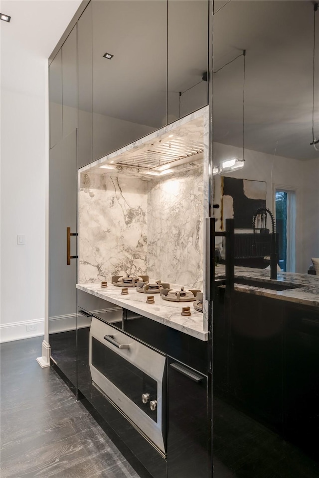 kitchen featuring a sink, light stone countertops, dark wood finished floors, modern cabinets, and dark cabinets