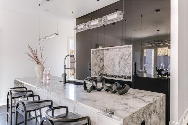6404 Lakehurst Ave, Dallas, TX 75230 - kitchen featuring a sink, light stone counters, baseboards, a kitchen breakfast bar, and modern cabinets
