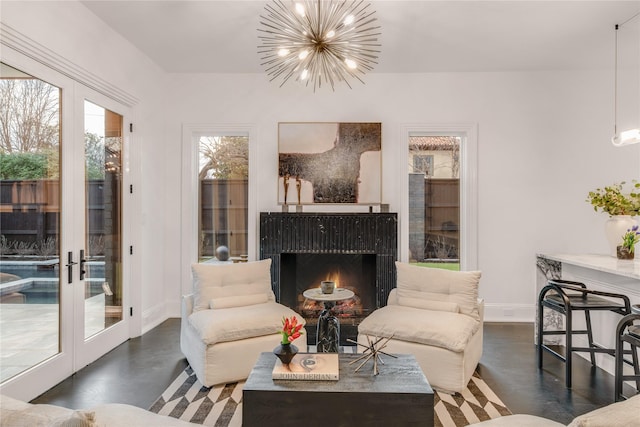 living area with an inviting chandelier, french doors, baseboards, and a lit fireplace