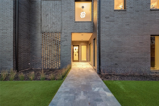 entrance to property with a yard and brick siding