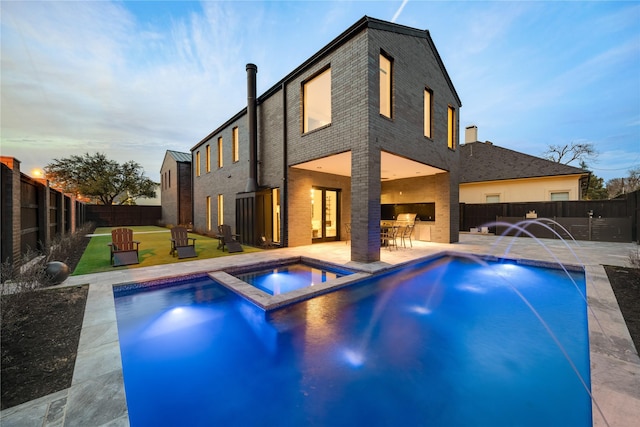 6404 Lakehurst Ave, Dallas, TX 75230 - back of house at dusk featuring brick siding, a patio, and a pool with connected hot tub