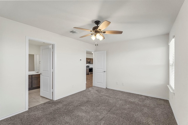 unfurnished bedroom with light colored carpet, visible vents, ensuite bathroom, and baseboards