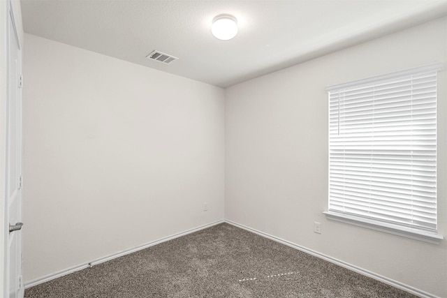 spare room featuring baseboards, visible vents, and carpet floors