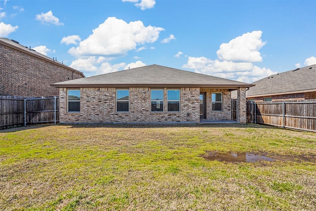 back of property featuring brick siding, a fenced backyard, and a lawn