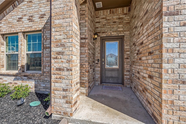 doorway to property with visible vents and brick siding