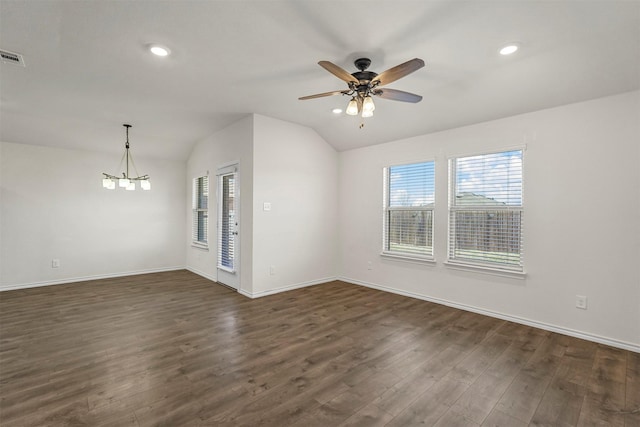 spare room featuring lofted ceiling, a healthy amount of sunlight, dark wood-style floors, and ceiling fan with notable chandelier