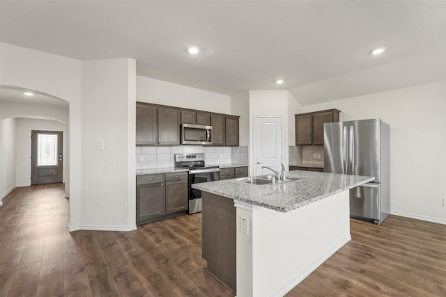 kitchen featuring dark wood-style floors, arched walkways, a sink, dark brown cabinets, and appliances with stainless steel finishes