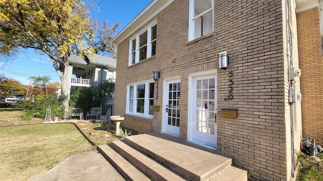 entrance to property featuring a lawn and brick siding