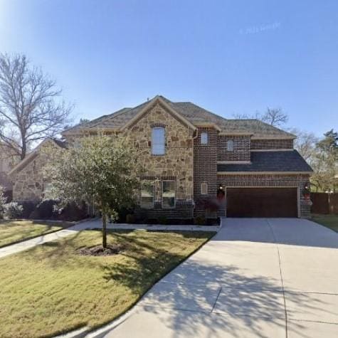 view of front of house featuring stone siding, a garage, driveway, and a front yard