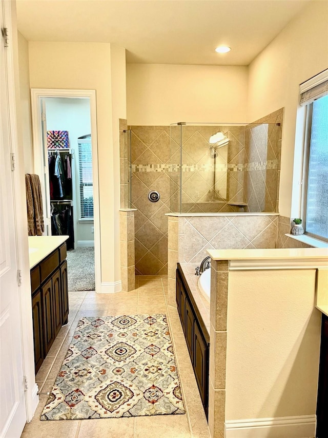 bathroom with vanity, tile patterned flooring, a walk in shower, a walk in closet, and a bath