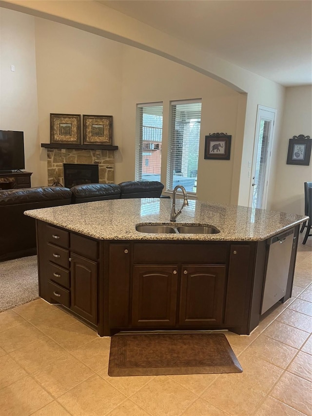 kitchen with open floor plan, dark brown cabinets, dishwasher, and a sink