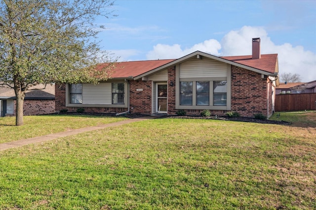 view of front facade featuring a front yard, fence, brick siding, and a chimney