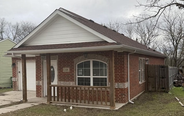 view of front facade with brick siding, concrete driveway, roof with shingles, covered porch, and an attached garage