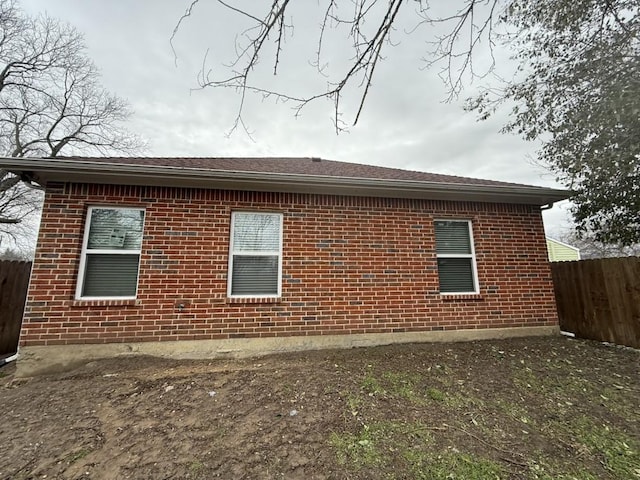 view of home's exterior featuring fence and brick siding