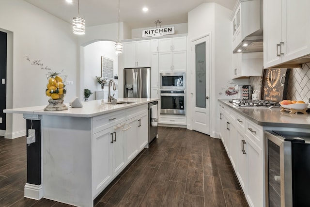 kitchen featuring a sink, backsplash, dark wood-style floors, wine cooler, and appliances with stainless steel finishes