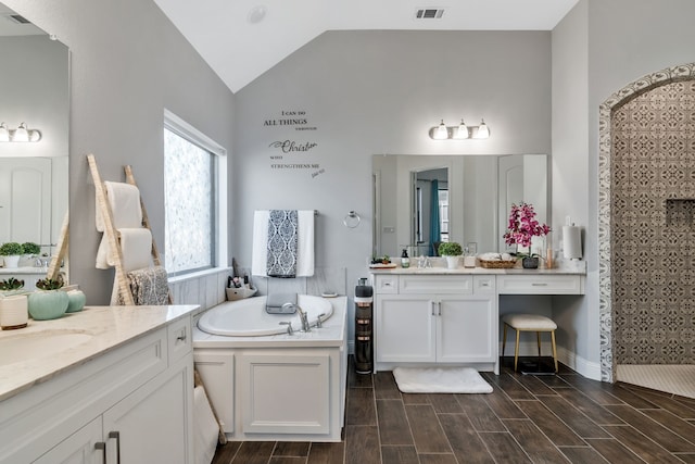 bathroom with visible vents, a garden tub, a sink, wood tiled floor, and vaulted ceiling